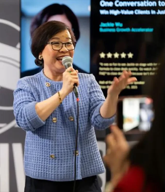 Jackie Wu speaking on stage with a microphone