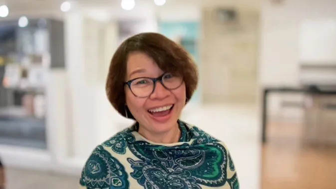 Jackie Wu laughing in a teal top at a table